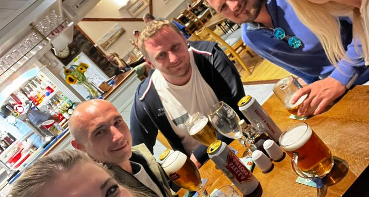 Group selfie of friends enjoying pints inside a cozy Welsh pub.