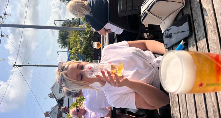 Woman sipping beer at an outdoor pub garden on a sunny day in Wales.