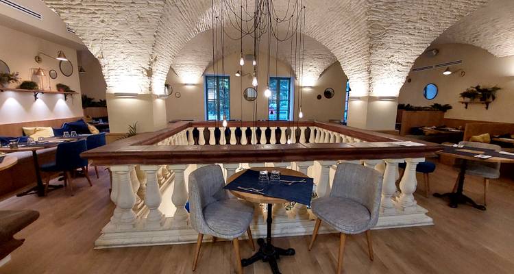 Stylish restaurant interior with vaulted brick ceiling, hanging lights and neatly set tables.
