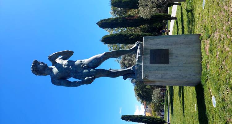 Replica statue of Michelangelo’s David standing on a plinth in a sunny public park.