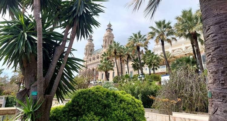 Palm-filled garden framing the ornate façade and twin towers of Monaco’s Salle Garnier Opera House.