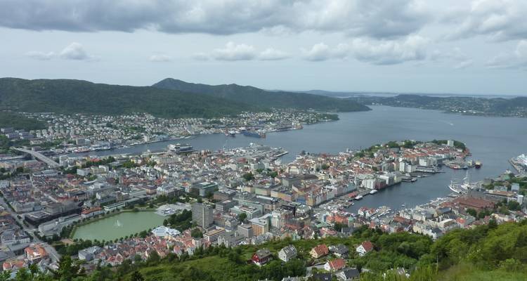Vue panoramique aérienne sur la ville de Bergen, son port et les fjords environnants sous un ciel partiellement nuageux.