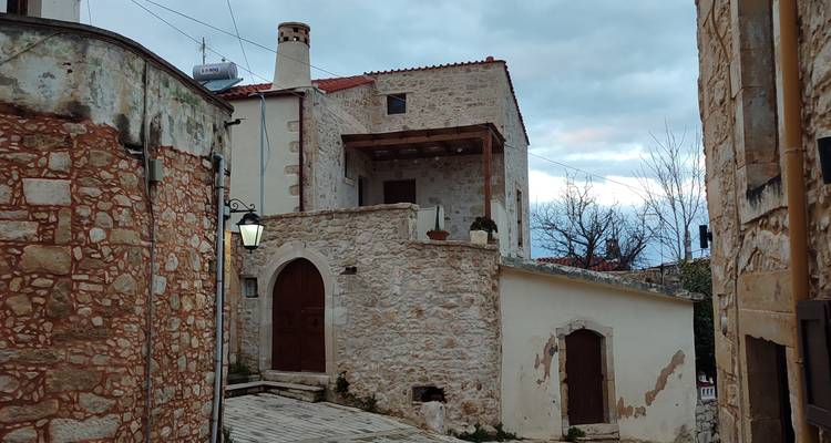 Stone houses along a narrow lane in a traditional hill village under overcast evening sky.