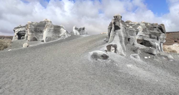 Des tours de tuf volcanique gris inhabituelles s'élevant d'un champ de cendre fine sous un ciel brillant.