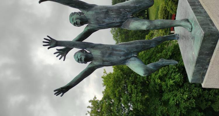 Statue en bronze d'enfants joyeux bondissant les bras levés contre un ciel gris au parc Vigeland.