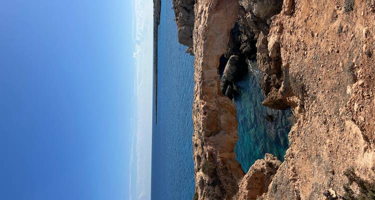 Rocky natural bridge over vivid blue water with open sea horizon