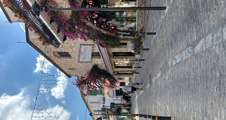 Picturesque village street with stone buildings, bougainvillea and boutique shops