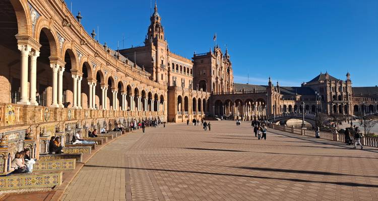 Lange arcade en tegels banken van Plaza de España vol met bezoekers die van de zon genieten