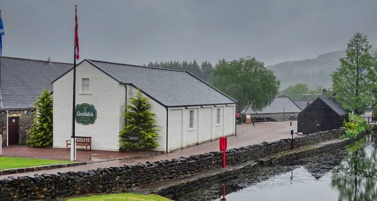 Small white canal-side building and lock on a rainy grey morning.