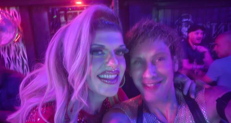 Two friends smiling in a neon-lit nightclub selfie