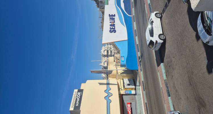 Street view of Sea Life aquarium facade and marina buildings against deep blue sky