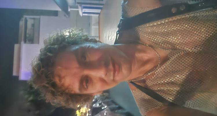 Nighttime selfie of a man wearing a shiny mesh top on a dimly lit street