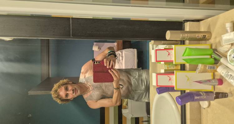 Mirror selfie of a man in a hotel bathroom wearing silver outfit