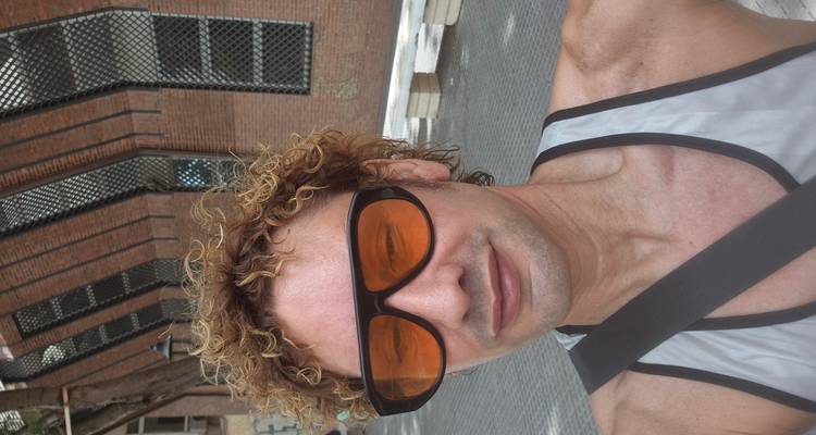 Close-up selfie with oversized orange sunglasses in an urban area