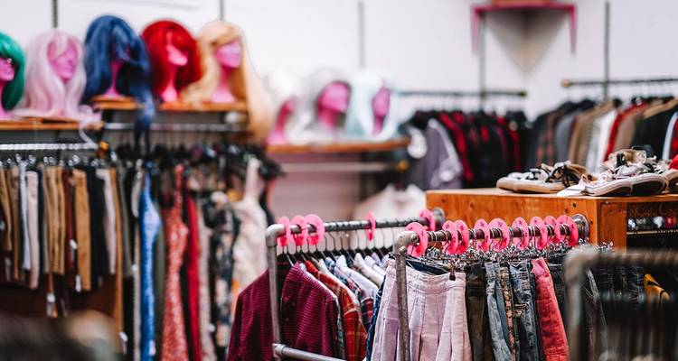 Des portants de vêtements colorés et des mannequins remplissent l'intérieur d'une boutique tendance.