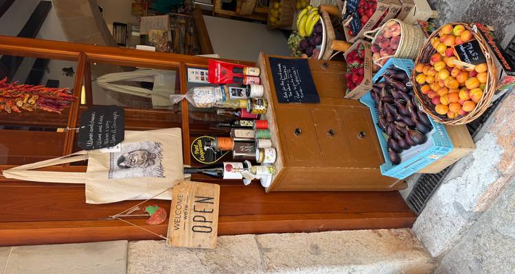 Devanture d'épicerie rustique avec des caisses de produits frais, des vins locaux et des panneaux faits à la main.
