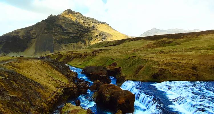 Vividly toned landscape of a mountain and river gorge with bright blue waterfall pools.