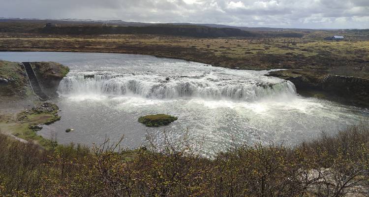 Broad, low waterfall (Faxi) spanning a river in a wide Icelandic plain.