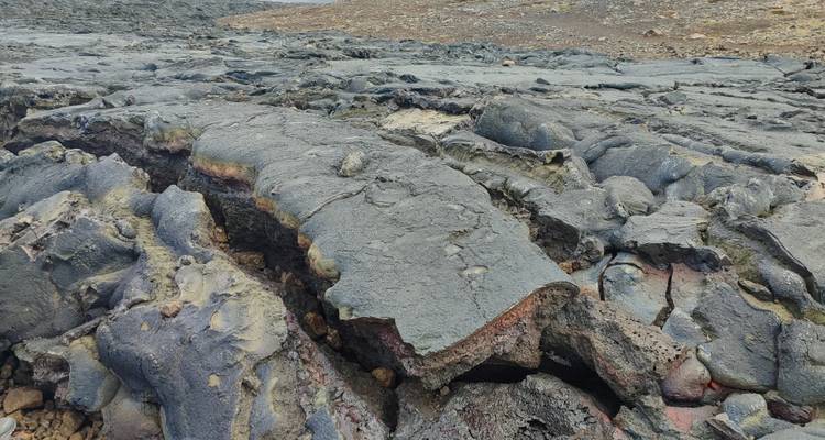 Rugged cracked lava surface stretching across a barren landscape.