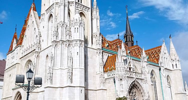Bright white Matthias Church with colorful tiled roof gleaming under a clear blue sky.