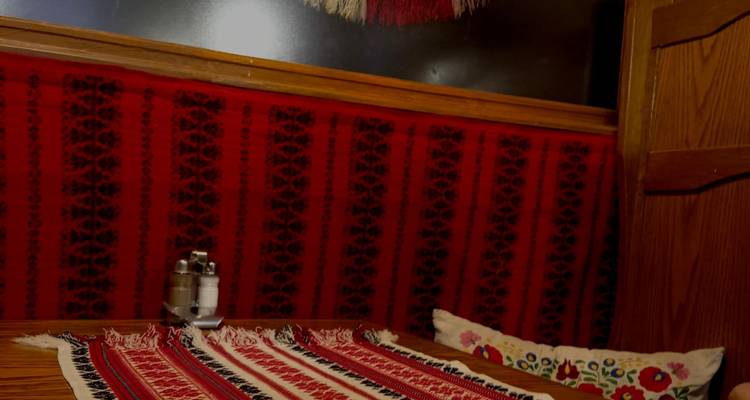 Small wooden booth interior decorated with traditional red patterned textiles and cushions.