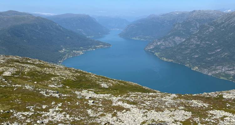 Un point de vue en haute altitude offrant une vue panoramique sur un fjord bleu sinueux s'enfonçant profondément entre des montagnes escarpées.