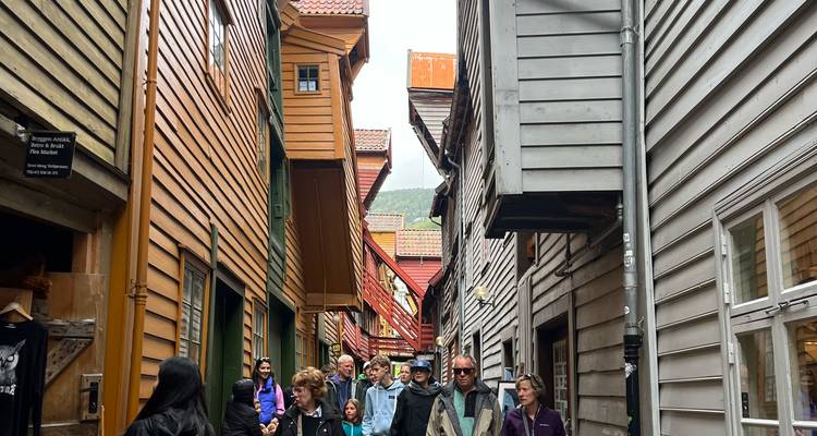 Ruelle étroite en bois de Bryggen remplie de touristes explorant les maisons commerciales historiques.