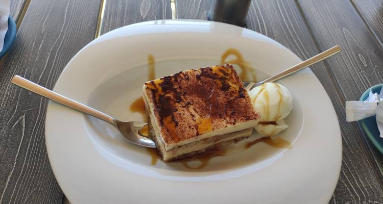 Plated dessert drizzled with caramel sauce accompanied by a scoop of vanilla ice cream.