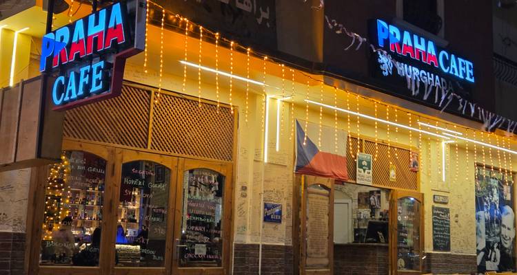 Nighttime close-up of Praha Café signboards illuminated with fairy lights.