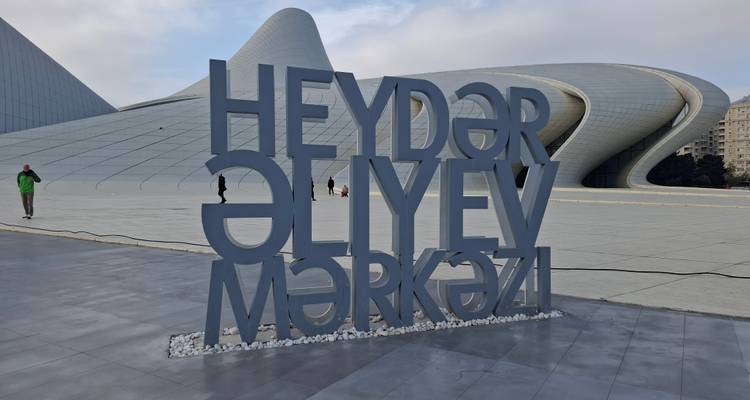Grand panneau indiquant « Heydar Aliyev Mərkəzi » devant le bâtiment iconique du musée aux formes courbes