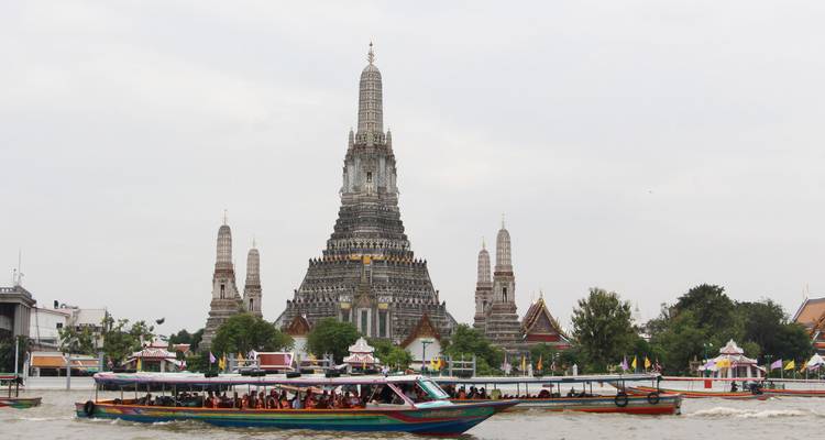 Bote de cola larga lleno de pasajeros en el río Chao Phraya con Wat Arun de fondo