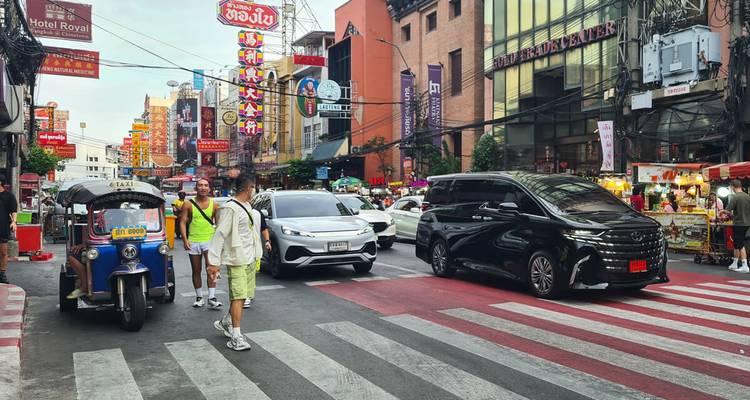 Calle colorida con luces de neón en el Barrio Chino de Bangkok con peatones, tuk-tuks y autos