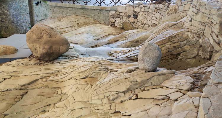Glacially polished rock surface with two large erratic boulders displayed in Lucerne’s Glacier Garden exhibit.