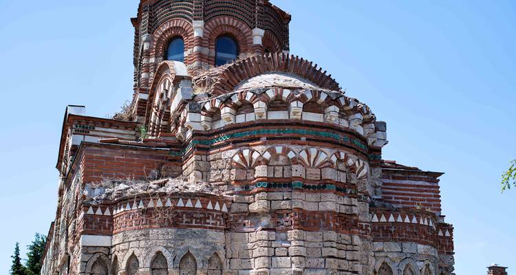 Vue latérale d'une église médiévale en brique usée par les intempéries contre un ciel bleu clair à Nesebar.