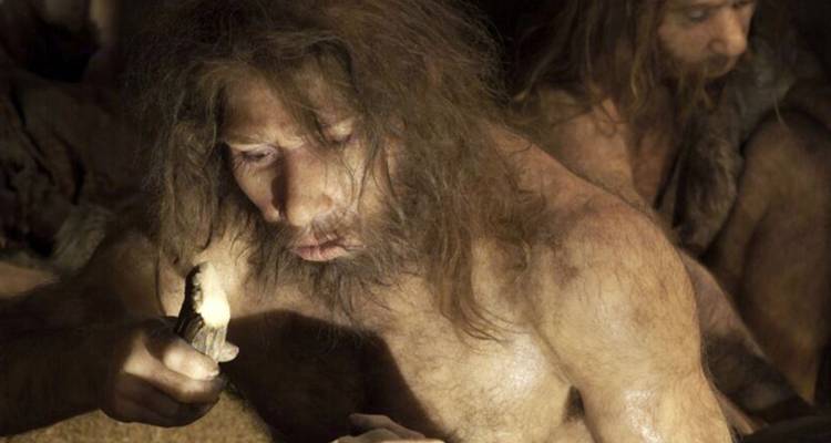 Realistische museumdiodrama van een Neanderthaler die een vonk slaat in zwak vuurlicht.