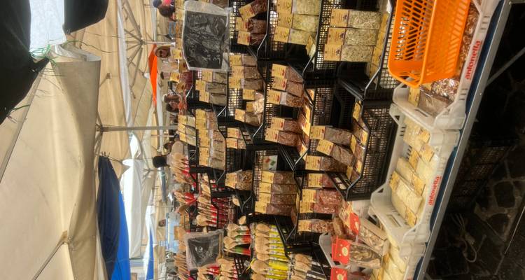Filas de especias y quesos empaquetados a la venta en un concurrido mercado de comida al aire libre.