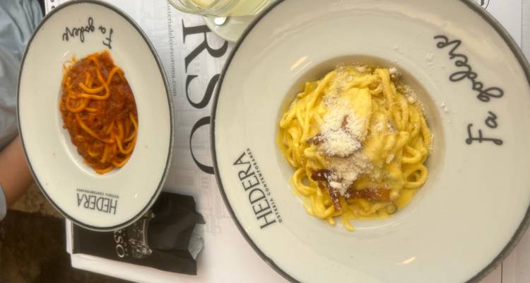 Dos platos de pasta cremosa - carbonara y ragù - servidos en una trattoria italiana.