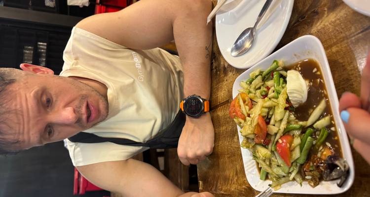 A man in a casual restaurant reacts to a plate of Thai papaya salad placed in front of him.