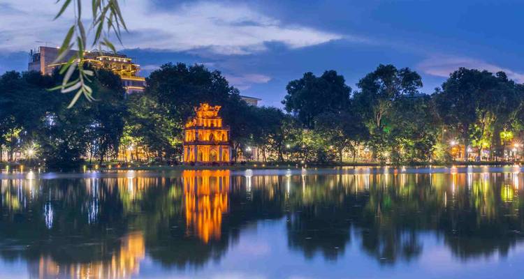 Turtle Tower illuminated on Hoan Kiem Lake with reflections during blue hour.