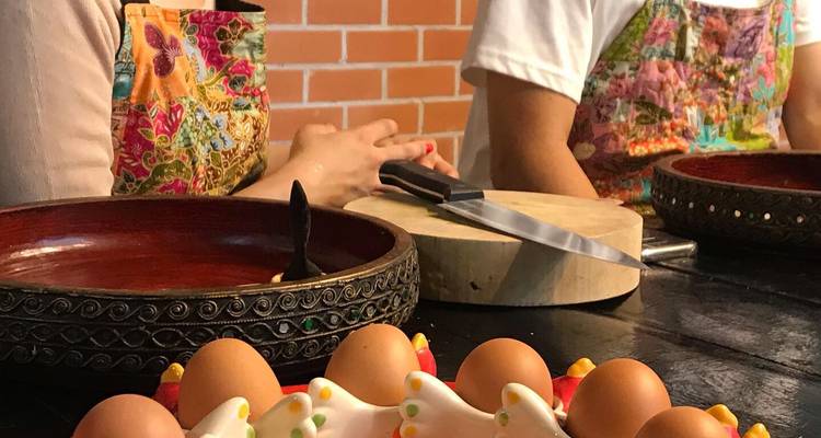 Cooking class workstation with bowls of eggs, chopping board, and participants wearing aprons.