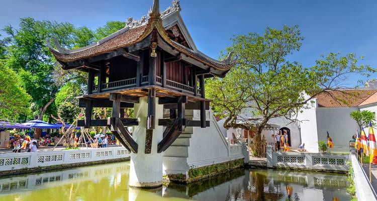 Historic One Pillar Pagoda rising over a lotus pond under clear blue sky.
