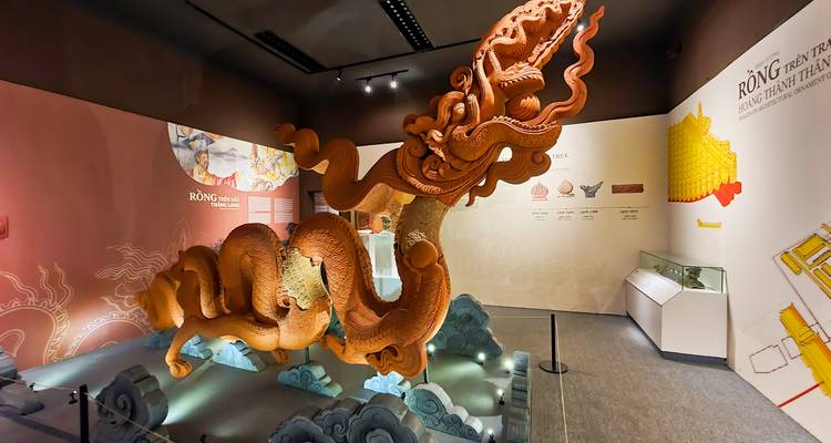 Museum exhibit featuring an elaborate orange dragon sculpture under spotlights.