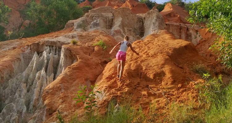 Young woman climbs a steep orange and white sand cliff in the Fairy Stream area near Mui Ne.