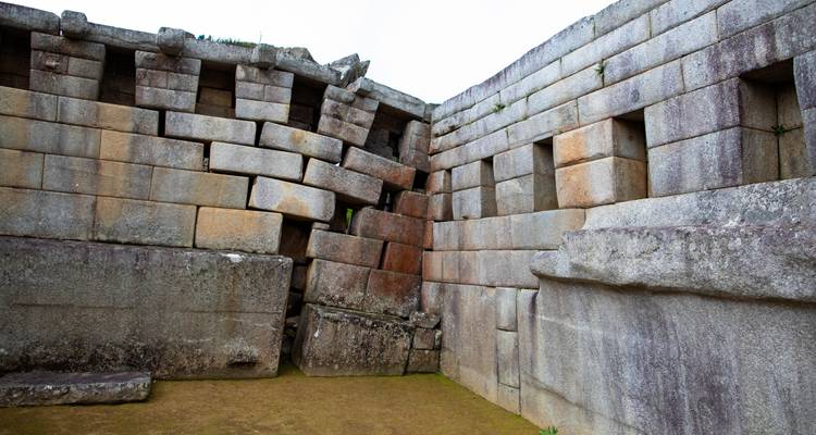 Massive, präzise behauene Steinblöcke bilden eine antike Inkamauer mit sichtbaren Erdbebenschäden.