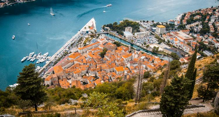 Point de vue surélevé surplombant la vieille ville fortifiée de Kotor et sa marina depuis un sentier de montagne en zigzag abrupt.