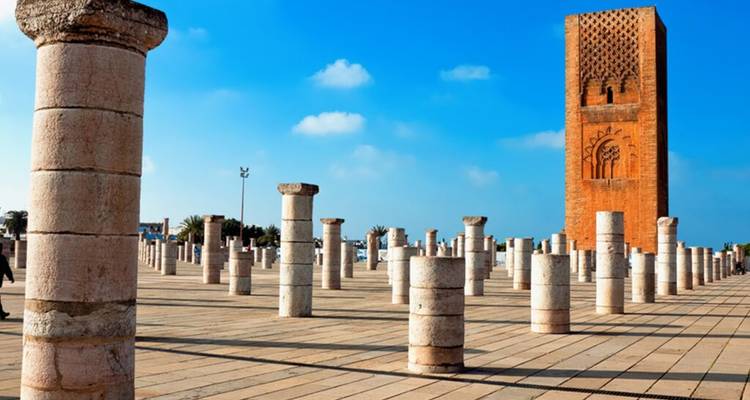Hassan Tower rising above rows of stone columns under a bright blue sky in Rabat.