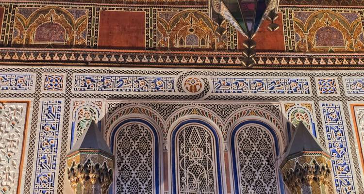 Richly decorated Moroccan interior wall with intricate tilework, carvings and geometric patterns.