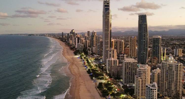 Avondopname vanuit de lucht van de Gold Coast wolkenkrabberstip met verlichte straten en lang zandstrand.