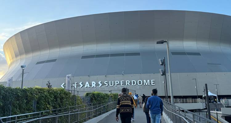 Les visiteurs empruntent la rampe vers l'extérieur massif et incurvé du Caesars Superdome au coucher du soleil.