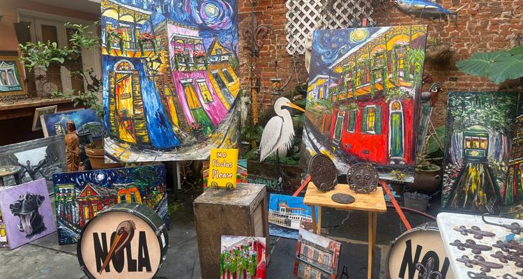 Marché d'art en cour rempli de peintures colorées, de tambours étiquetés « NOLA » et de décor éclectique.